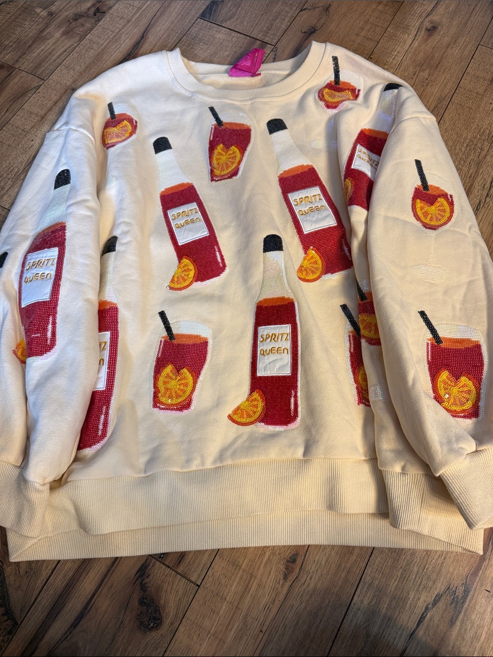 QUEEN OF SPARKLES Cream Sweater with Red & Orange Spritz Bottle Motif